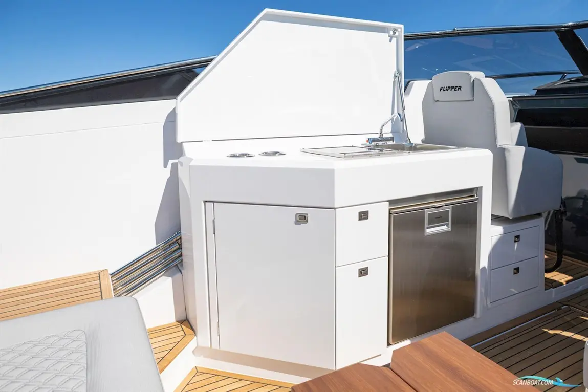 Modern boat kitchenette featuring a sink, storage cabinets, and a stainless steel refrigerator against a clear blue sky.